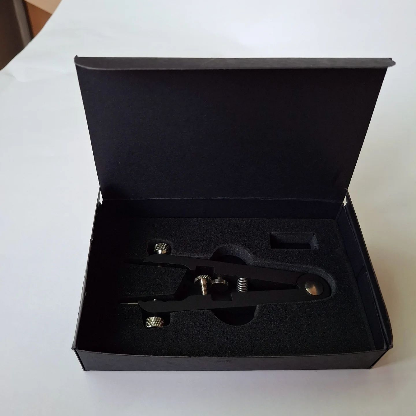 Black rigid box with die-cut foam insert holding a precision instrument